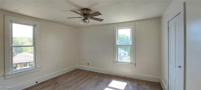 carpeted empty room with ceiling fan and plenty of natural light