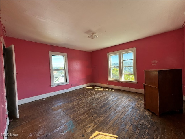 empty room with a healthy amount of sunlight and dark hardwood / wood-style flooring