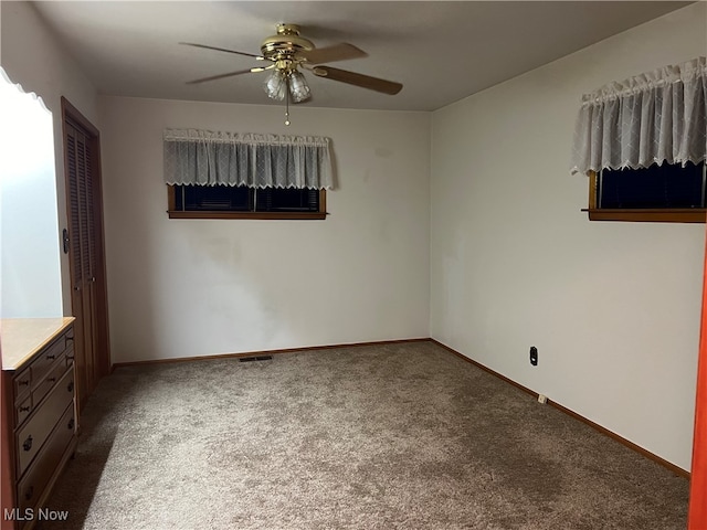 unfurnished room featuring ceiling fan and dark colored carpet