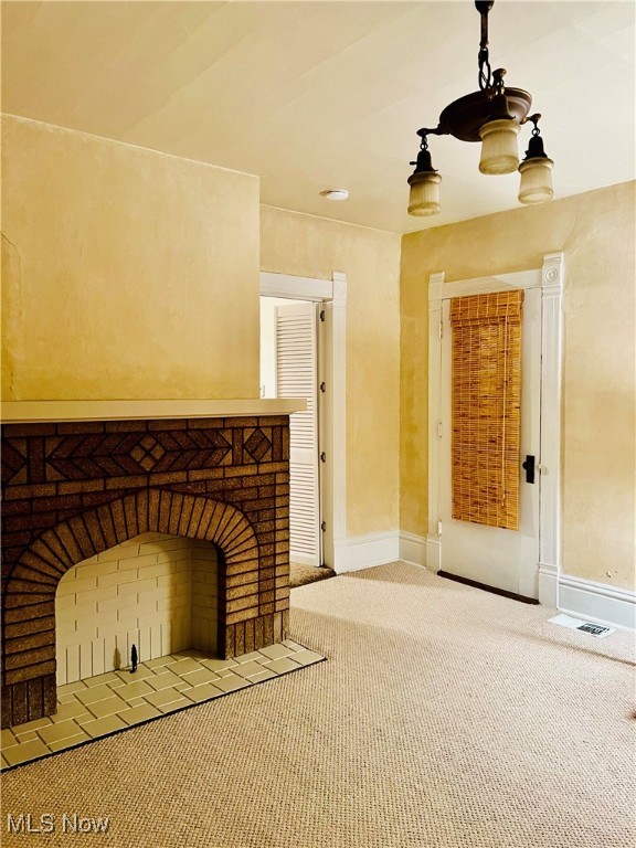 unfurnished living room featuring a brick fireplace and carpet