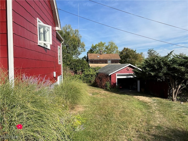 view of yard with a garage and an outbuilding