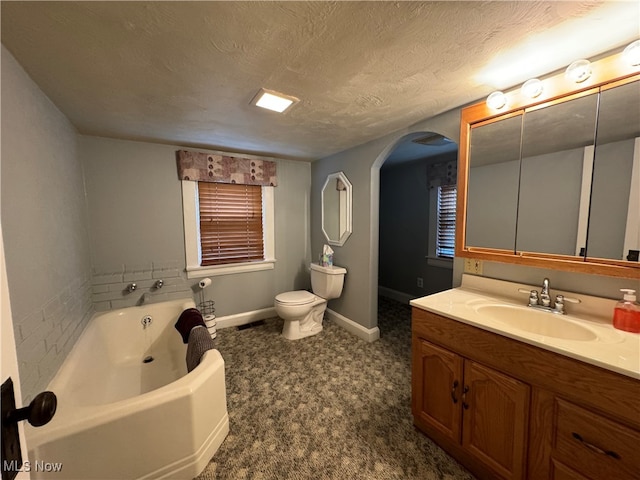 bathroom featuring vanity, a textured ceiling, toilet, and a washtub