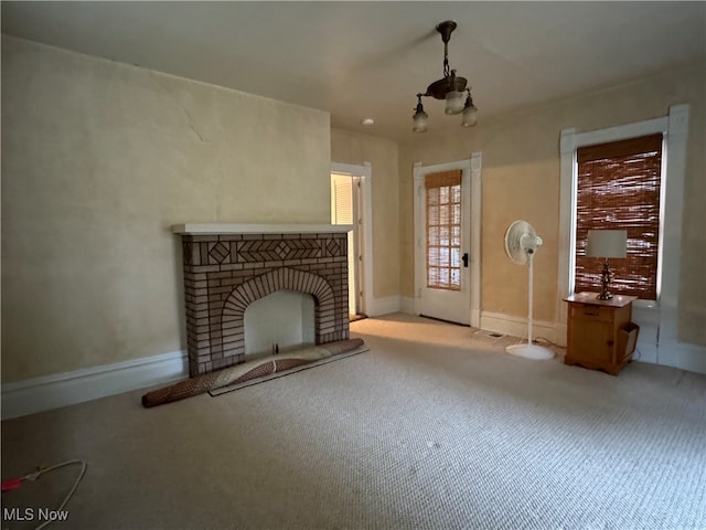 unfurnished living room with a fireplace, a chandelier, and light colored carpet