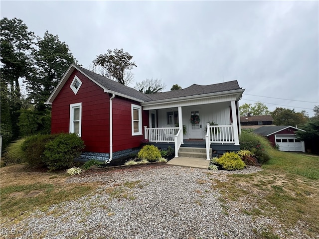 view of front facade featuring a garage, covered porch, and an outbuilding