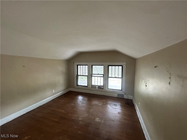 additional living space featuring vaulted ceiling and dark hardwood / wood-style flooring