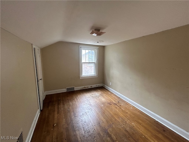 additional living space with wood-type flooring and vaulted ceiling