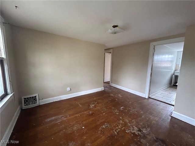 unfurnished bedroom with ensuite bathroom and hardwood / wood-style floors