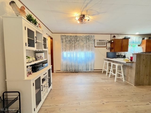 kitchen featuring a kitchen breakfast bar, kitchen peninsula, a wall mounted AC, and light hardwood / wood-style flooring