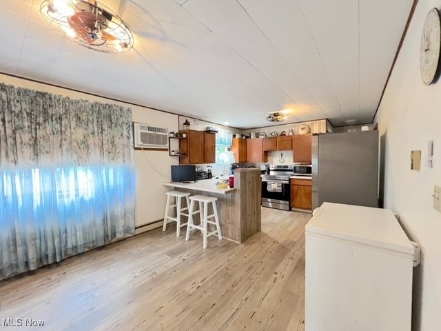 kitchen with a breakfast bar, a wall unit AC, kitchen peninsula, light hardwood / wood-style flooring, and appliances with stainless steel finishes