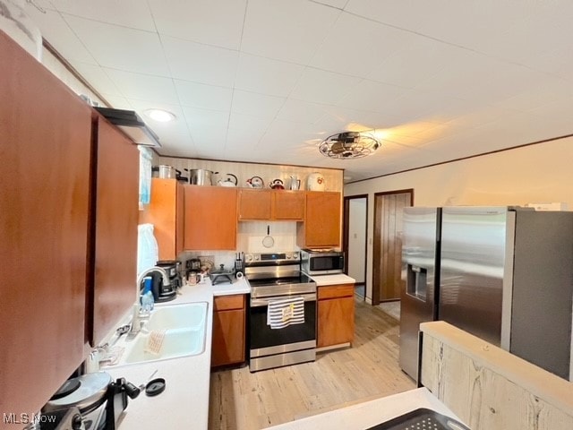 kitchen with light wood-type flooring, appliances with stainless steel finishes, and sink