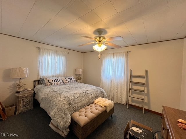 bedroom featuring ceiling fan, dark colored carpet, and multiple windows