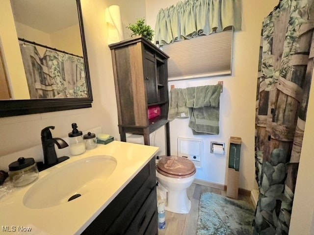 bathroom featuring wood-type flooring, vanity, and toilet