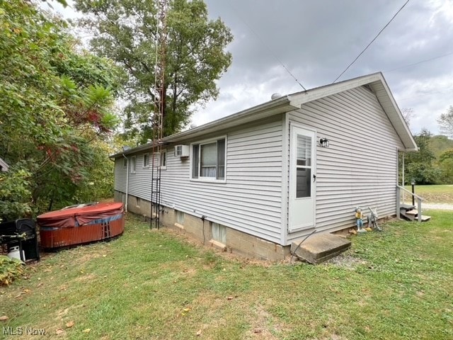 view of property exterior with a lawn and a wall mounted air conditioner