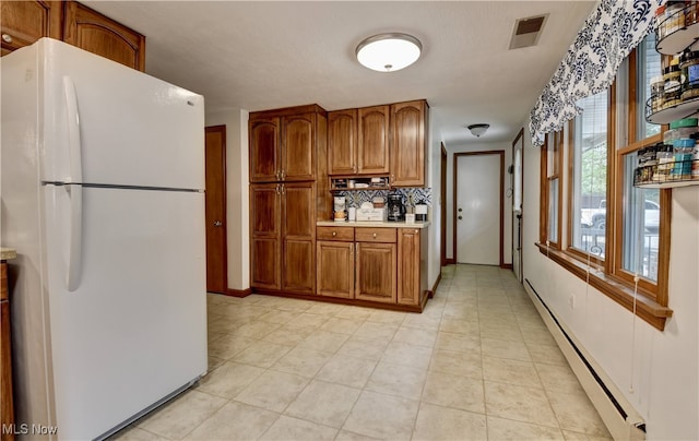 kitchen with backsplash, white refrigerator, baseboard heating, and light tile patterned flooring