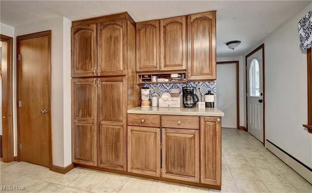 kitchen featuring light tile patterned flooring, baseboard heating, and decorative backsplash