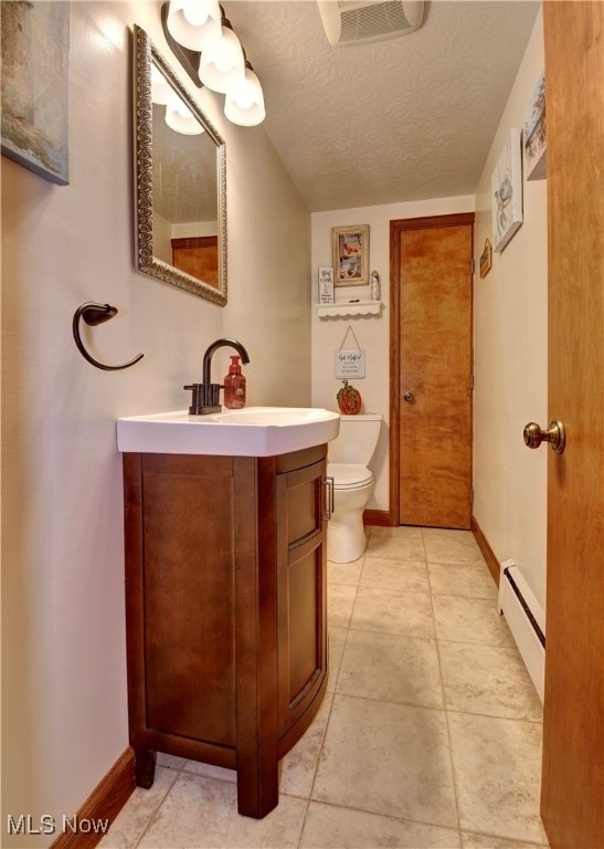 bathroom featuring tile patterned flooring, a textured ceiling, baseboard heating, vanity, and toilet