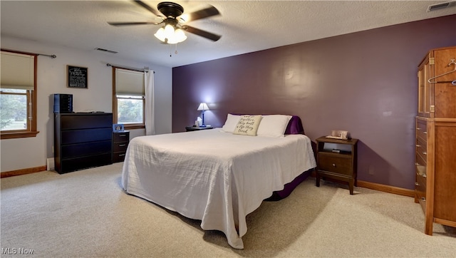 carpeted bedroom with ceiling fan, multiple windows, and a textured ceiling