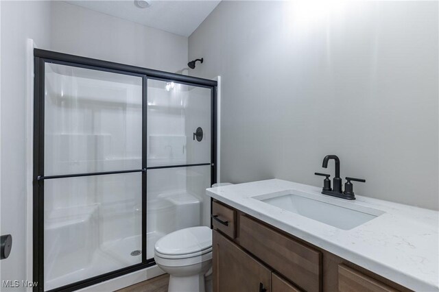 bathroom with hardwood / wood-style flooring, toilet, walk in shower, and vanity