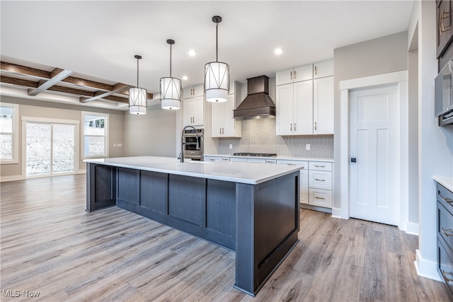 kitchen with custom range hood, pendant lighting, white cabinets, and light wood-type flooring