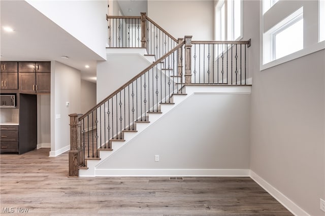 staircase featuring wood-type flooring and a high ceiling