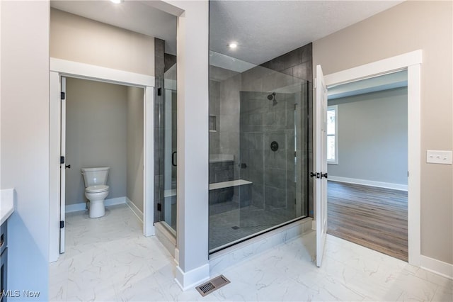 bathroom featuring vanity, walk in shower, and toilet