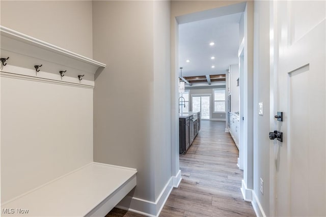 mudroom featuring sink, beamed ceiling, and light wood-type flooring