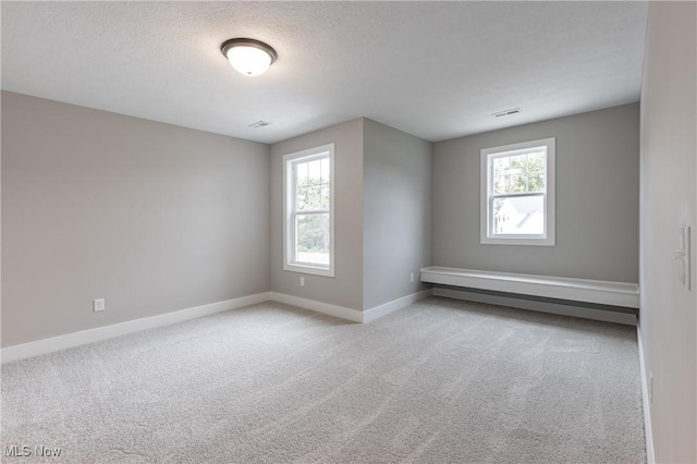 carpeted empty room featuring a textured ceiling