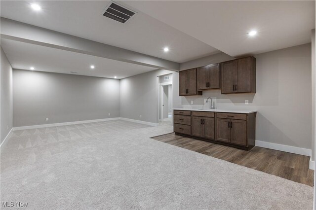 kitchen featuring dark brown cabinets, sink, and carpet flooring