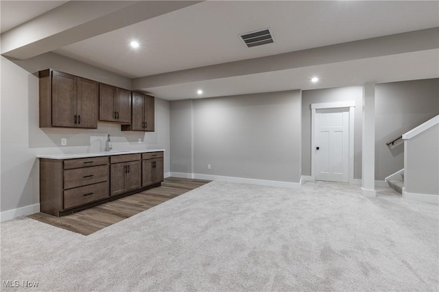 bar featuring light colored carpet, dark brown cabinetry, and sink