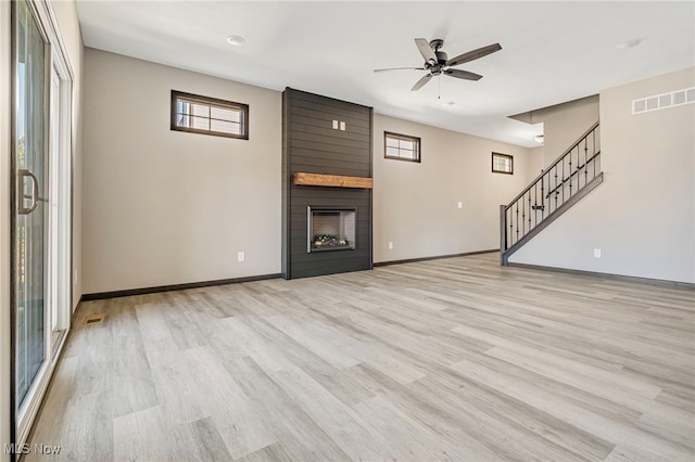 unfurnished living room with a large fireplace, ceiling fan, and light hardwood / wood-style flooring