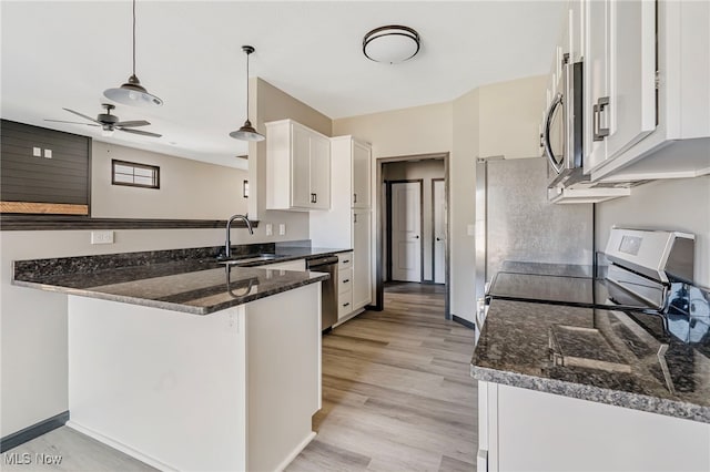 kitchen with white cabinetry, kitchen peninsula, stainless steel appliances, ceiling fan, and sink