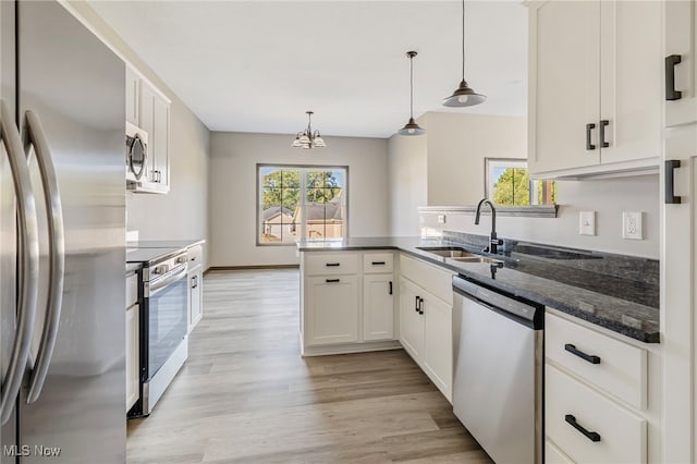 kitchen featuring sink, white cabinetry, light hardwood / wood-style flooring, appliances with stainless steel finishes, and decorative light fixtures