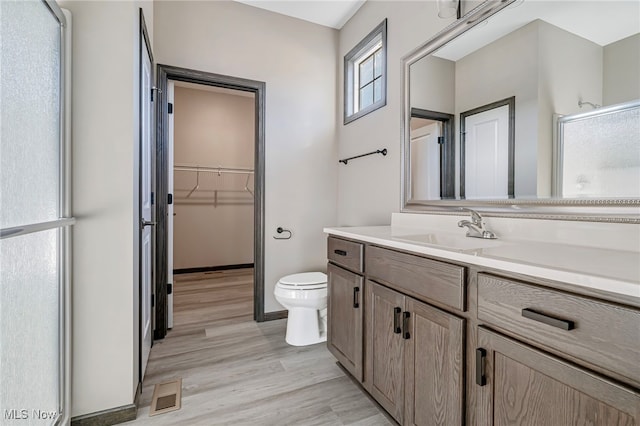 bathroom featuring vanity, hardwood / wood-style floors, toilet, and an enclosed shower