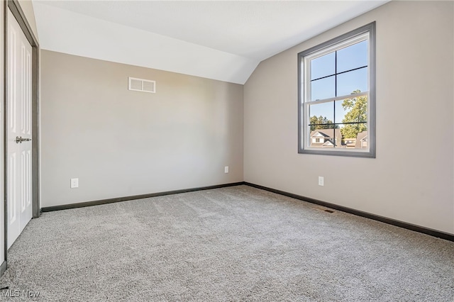 carpeted empty room with lofted ceiling