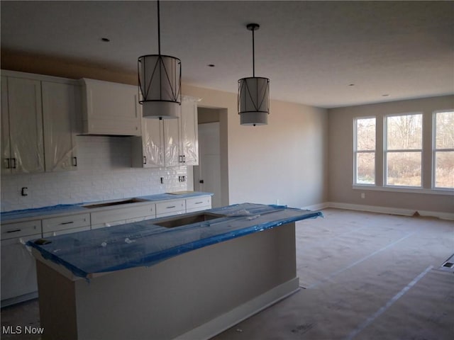 kitchen featuring decorative light fixtures, cooktop, white cabinetry, and backsplash