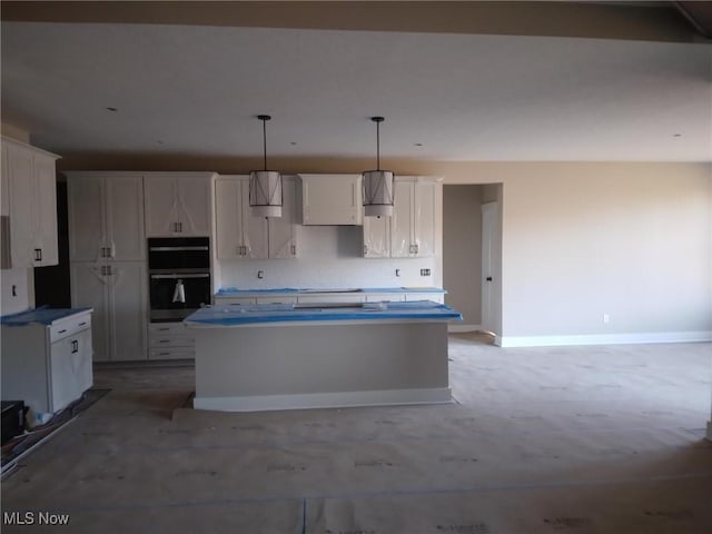 kitchen with white cabinets, black double oven, a kitchen island, and decorative light fixtures