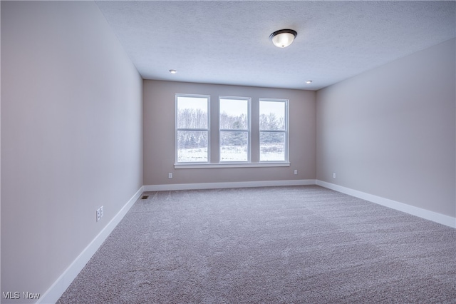 unfurnished room with a textured ceiling, light carpet, and baseboards