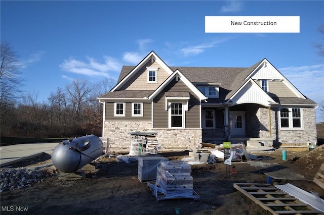 view of front facade with a shingled roof and stone siding