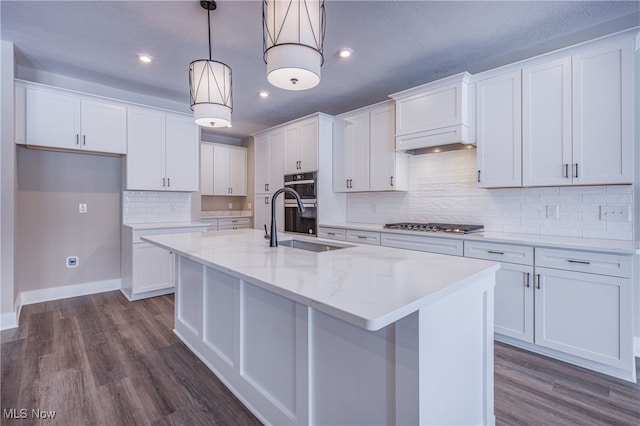 kitchen with a kitchen island with sink, decorative light fixtures, and white cabinets