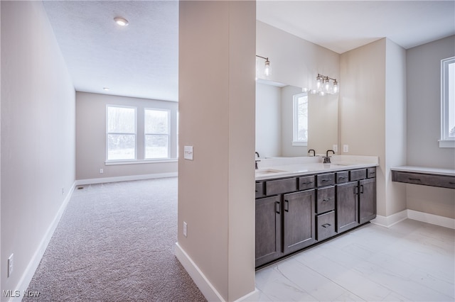 full bathroom featuring a sink, baseboards, and double vanity