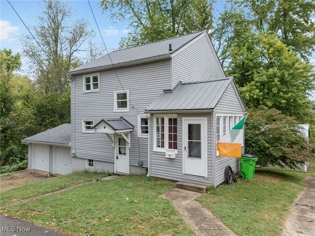 rear view of house featuring a garage and a yard