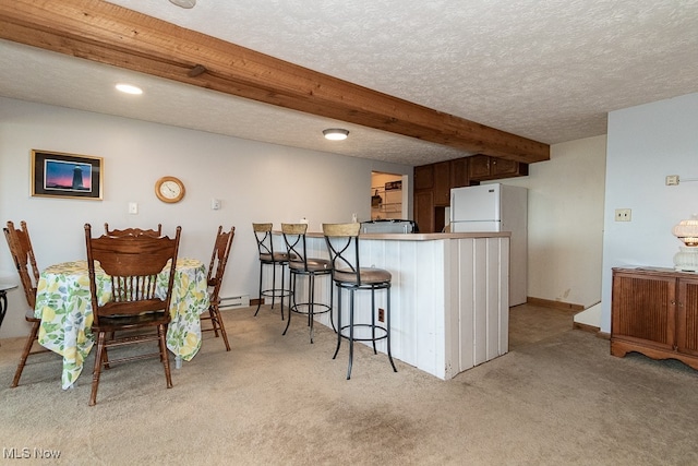 interior space featuring kitchen peninsula, a textured ceiling, a kitchen bar, beam ceiling, and light carpet