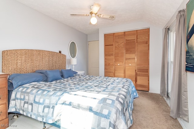 bedroom with ceiling fan, lofted ceiling, a textured ceiling, a closet, and light colored carpet