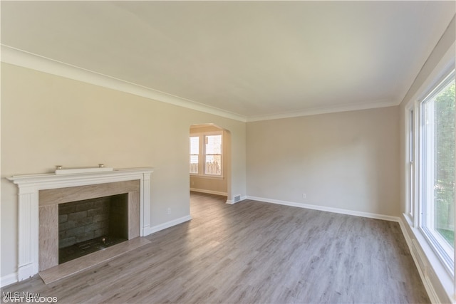 unfurnished living room with light hardwood / wood-style floors, plenty of natural light, a fireplace, and crown molding