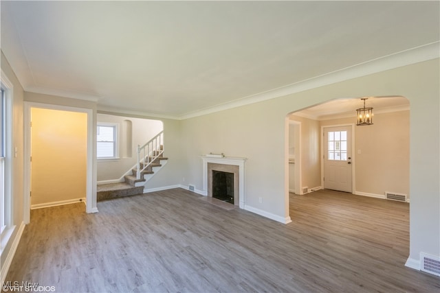 unfurnished living room featuring wood-type flooring, a notable chandelier, and crown molding