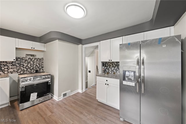 kitchen featuring appliances with stainless steel finishes, white cabinetry, light stone counters, tasteful backsplash, and light wood-type flooring