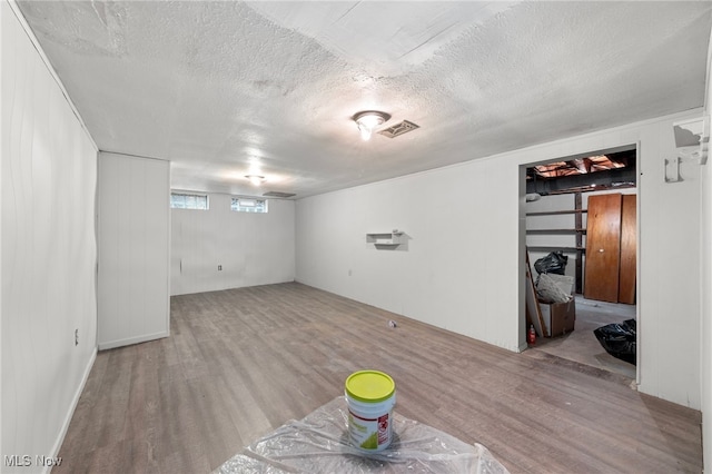 basement featuring light hardwood / wood-style flooring and a textured ceiling