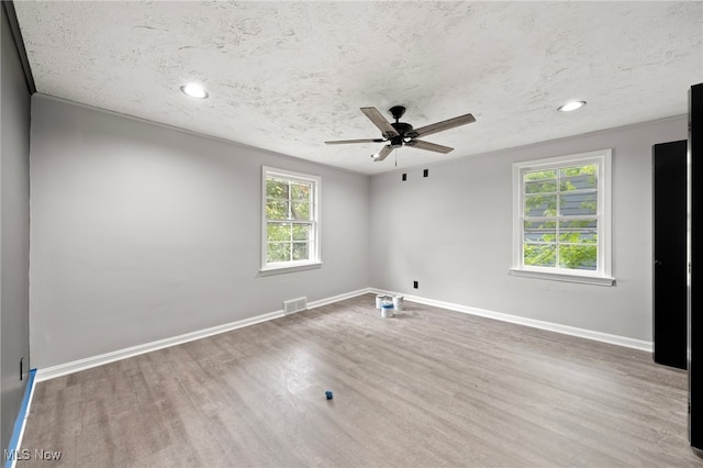 spare room with ceiling fan, a textured ceiling, plenty of natural light, and wood-type flooring