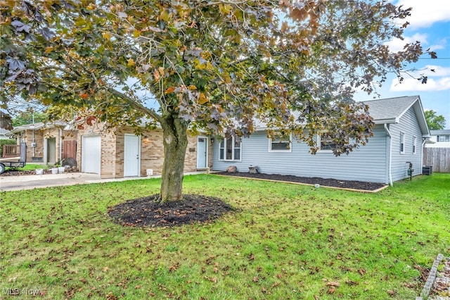 view of property hidden behind natural elements featuring central air condition unit, a garage, and a front lawn