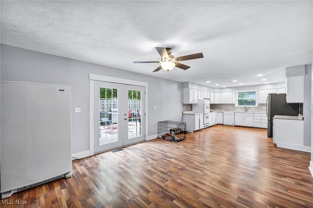 unfurnished living room featuring sink, ceiling fan, a textured ceiling, hardwood / wood-style floors, and french doors